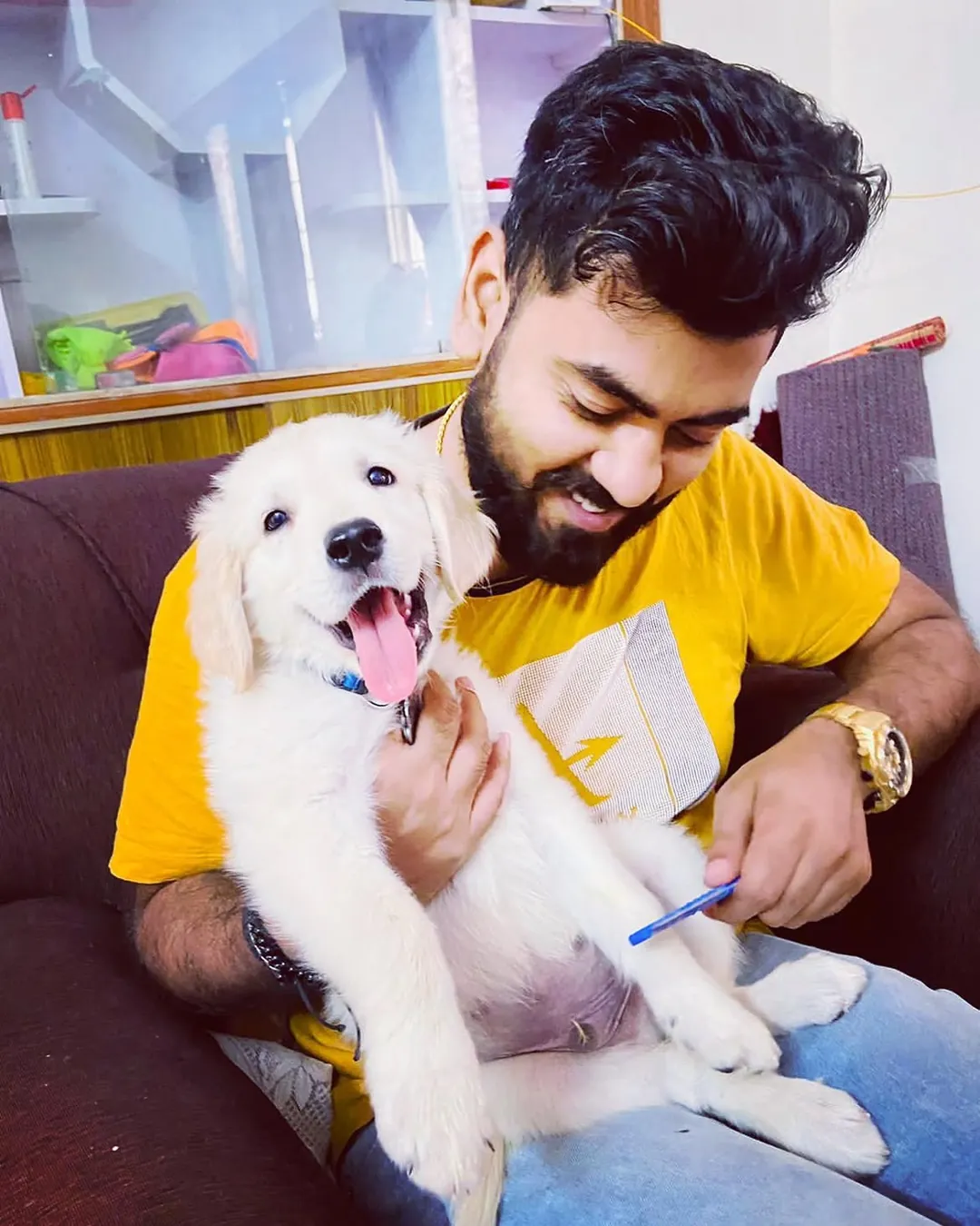 Rahul holding puppy Dexter on the sofa, both smiling.